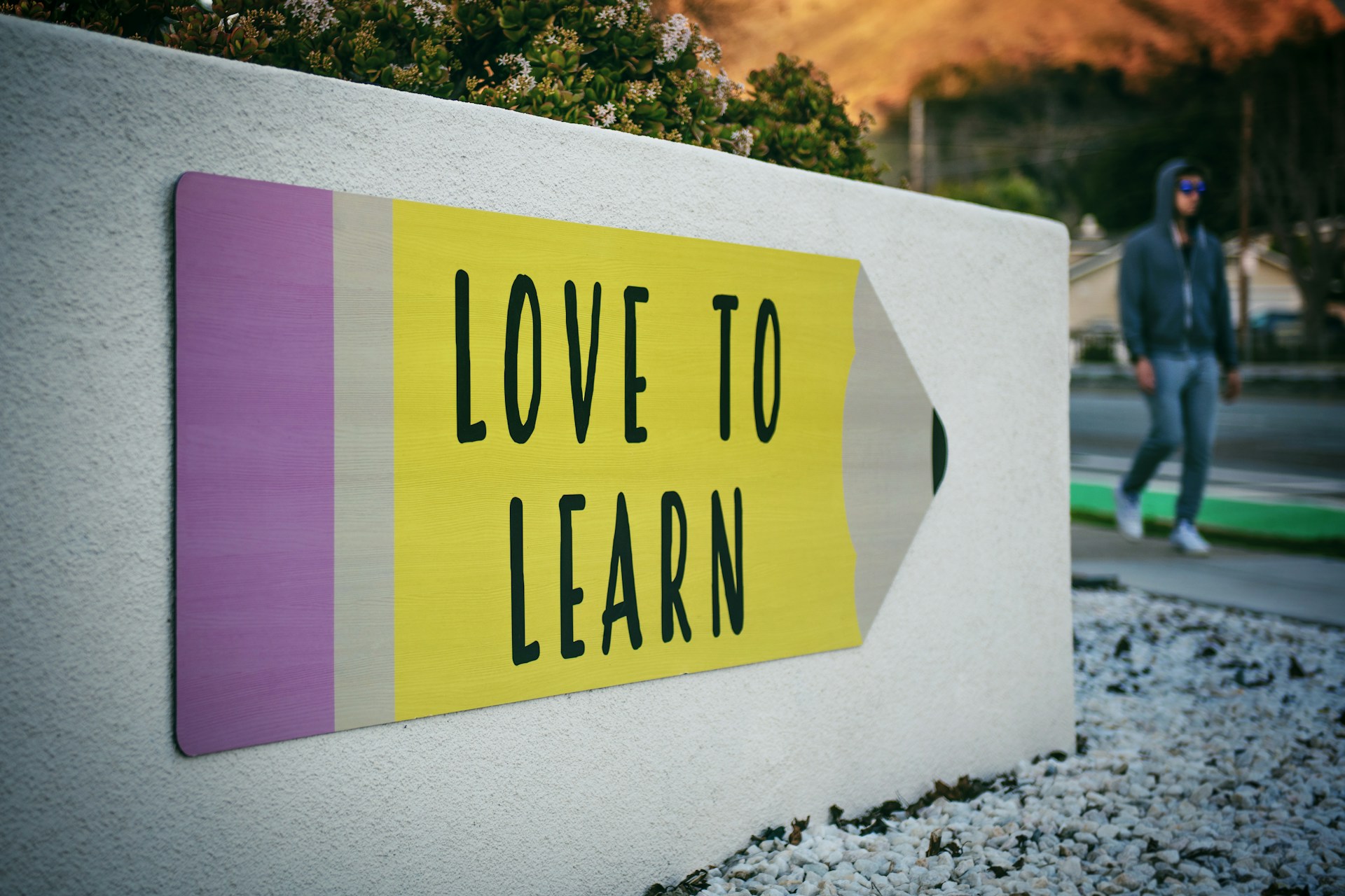 I love learn board with a pencil in the wall with a walking man in the backgroud